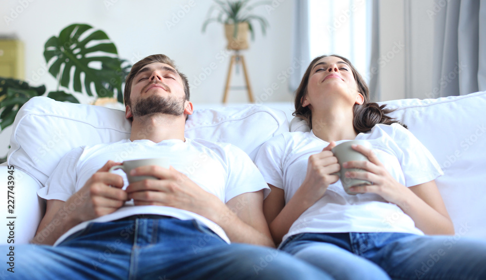 Fototapeta premium Smiling beautiful couple sitting on a sofa and dreaming about new home.