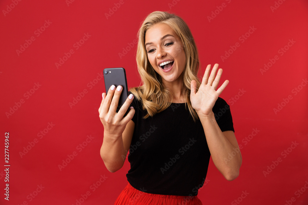 Fototapeta premium Portrait of a cheerful young woman isolated over red