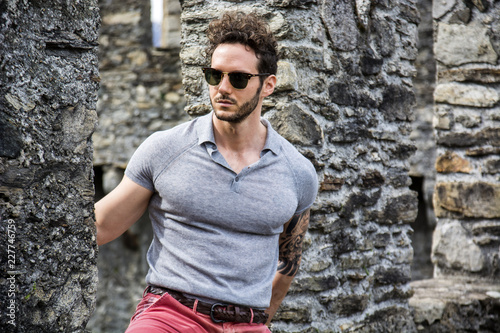 Attractive man outdoor in old European castle, in Switzerland. Athletic build, with tight t-shirt and sunglasses © theartofphoto