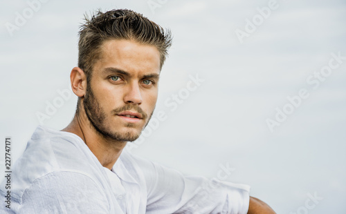Handsome Young Man in Trendy Attire, on a Beach in a Sunny Summer Day, Wearing a White Shirt
