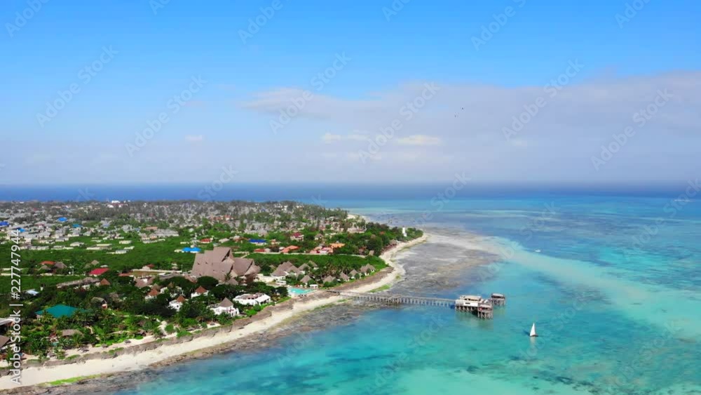 Aerial view of beautiful tropical island in the ocean, Zanzibar, Tanzania. Paradise beach with white coastal line, clear blue water and small boats rushing in the centre Aerial view of beautiful tropical island in the ocean, Zanzibar, Tanzania. Paradise beach with white coastal line, clear blue water and small boats rushing in the centre
