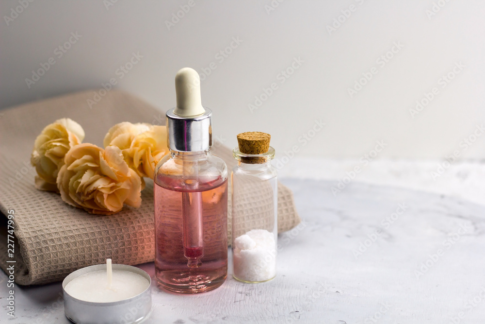 aroma oil  sea salt bottles fresh flowers on towel marble table  spa welness concept copy space