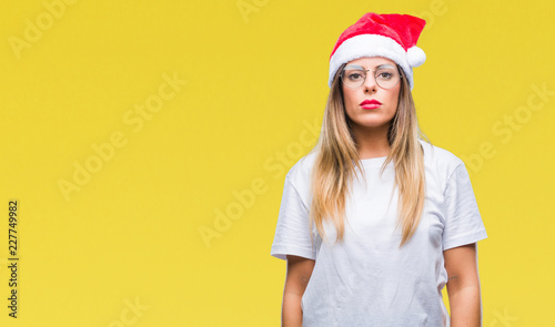 Young beautiful woman wearing christmas hat over isolated background with serious expression on face. Simple and natural looking at the camera. © Krakenimages.com
