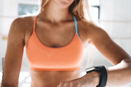 Photo fit woman after workout session checks results on smartwatch in fitness app..Sporty girl wearing sport tracker wristband arm