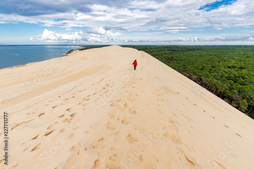 Woman walking on large sand dune photo