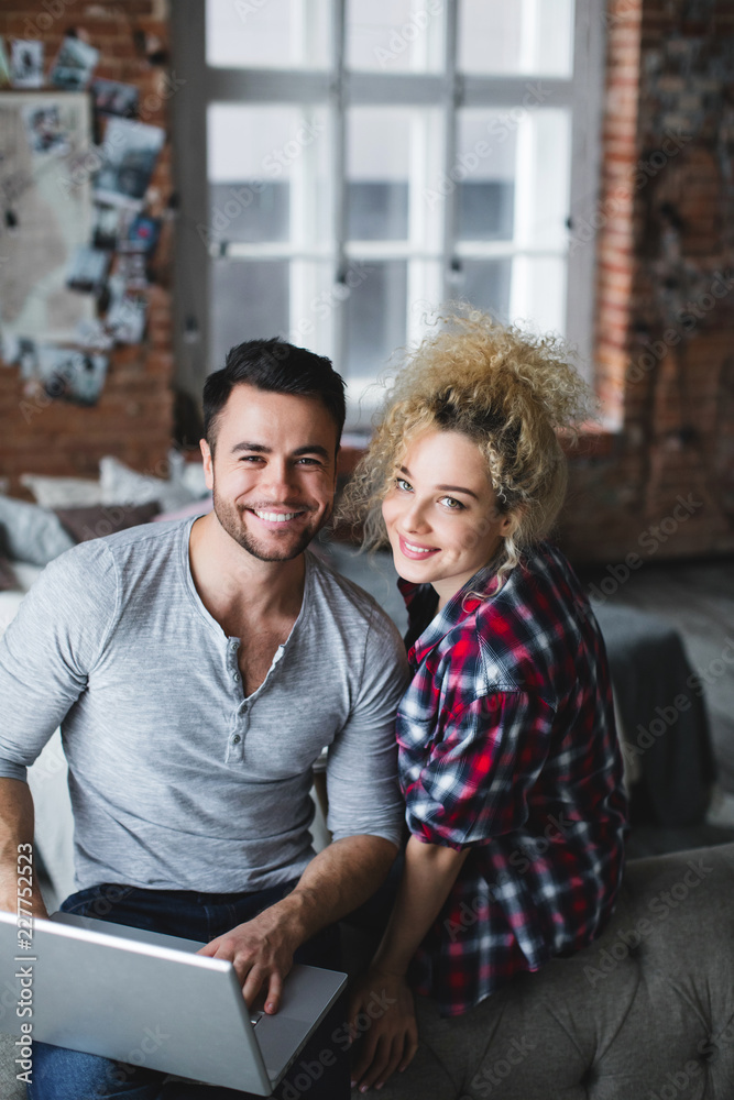 Portrait of beautiful young couple using laptop on the sofa at home. Portrait of beautiful young couple using laptop on the sofa at home.