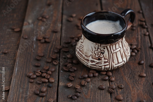 Coffee cup with beans on dark wood background