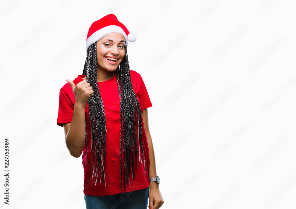 Young braided hair african american girl wearing christmas hat over isolated background doing happy thumbs up gesture with hand. Approving expression looking at the camera with showing success.