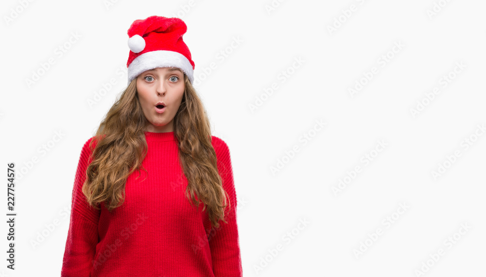 Young blonde woman wearing santa claus hat scared in shock with a surprise face, afraid and excited with fear expression Young blonde woman wearing santa claus hat scared in shock with a surprise face, afraid and excited with fear expression