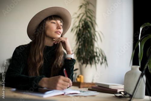 Portrait of young pensive writer looking for inspiration, brainstorming. Stylish freelancer working from home, focus on face