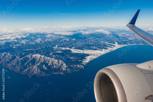 aerial view of airplane wing and landscape of coastline, sea and island in Hokkaido, Japan