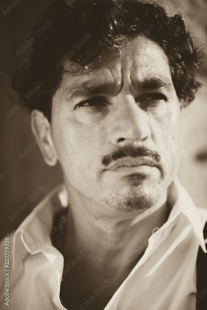 Obraz premium Portrait of a man with an interesting face typical of southern Italy, that can be defined both handsome or ugly, with black hair, moustaches, white skirt.