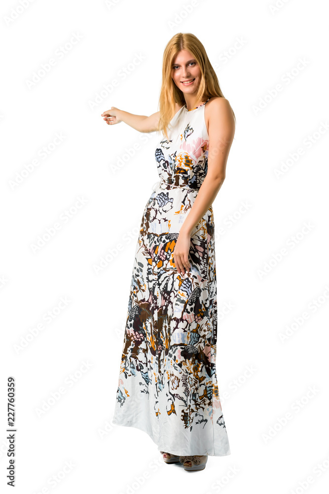 Blonde young girl in a summer dress pointing back with the index finger presenting a product on isolated white backgroun Blonde young girl in a summer dress pointing back with the index finger presenting a product on isolated white backgroun