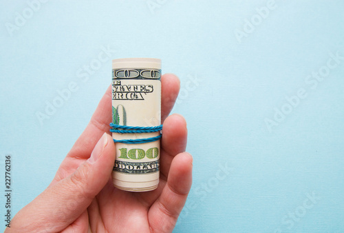 dollar money rolled into a pipe in a woman s hand on a blue background
