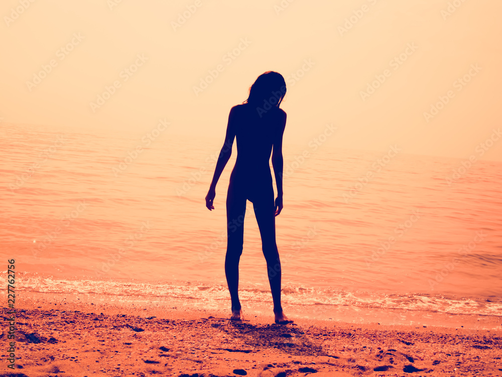 Φωτογραφία Silhouette of a skinny young girl walking along the beach