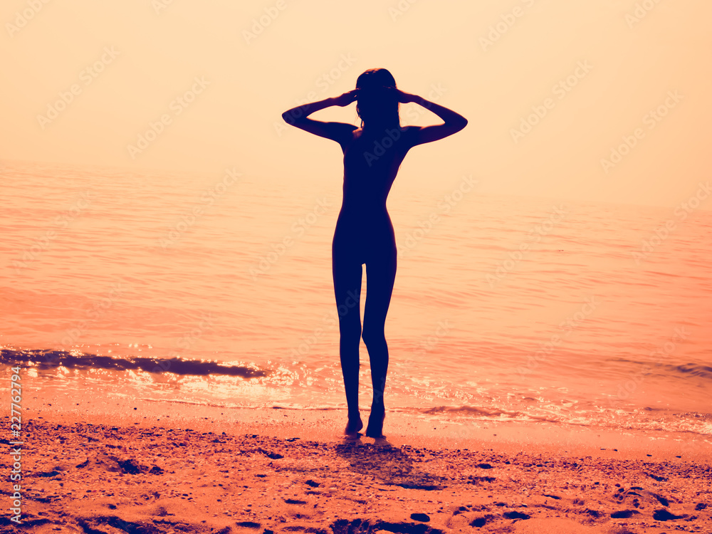 Φωτογραφία Silhouette of a skinny young girl walking along the beach