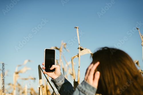 Beautiful young r woman using smart phone at corn field