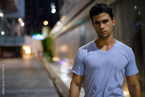 Young handsome Hispanic man exploring the city streets at night