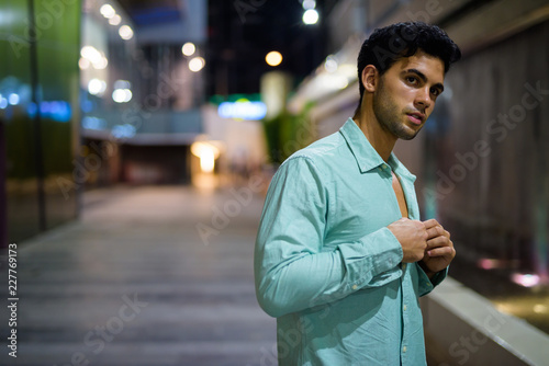 Young handsome Hispanic man exploring the city streets at night