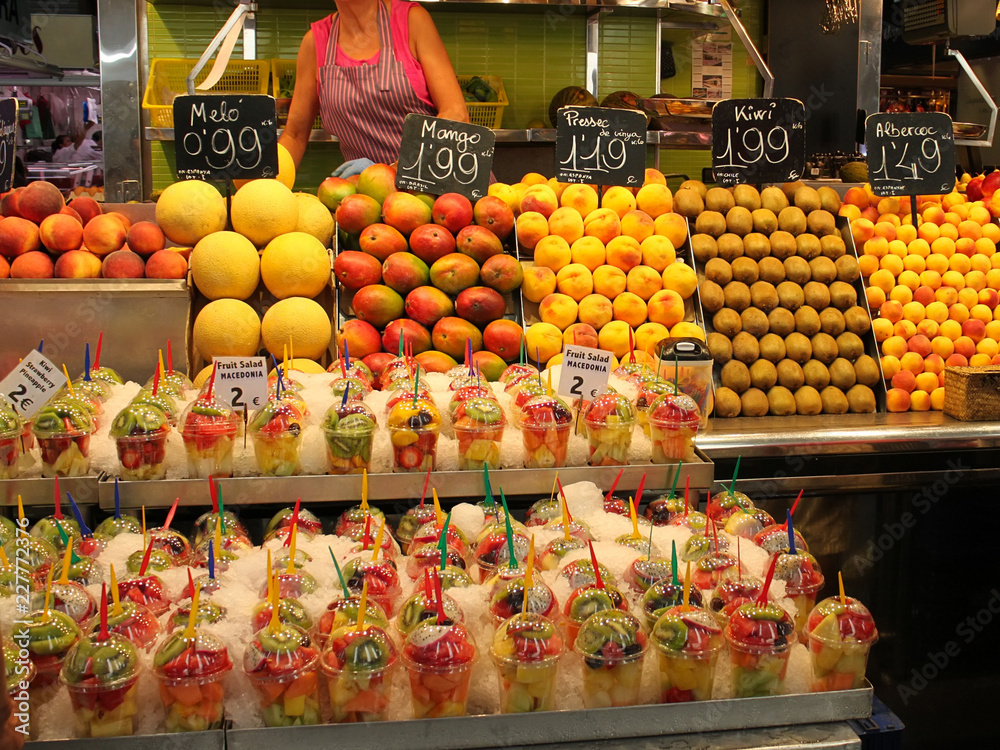 a lot of fruit salads in plastic cups, berries, fruits on the market counter with prices in euros