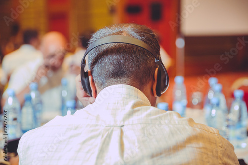 Unrecognizable people using in ear headphones for translation during event photo