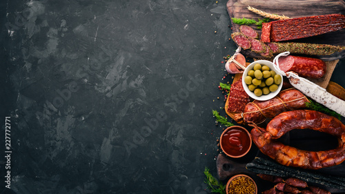 Assortment of salami and snacks. Sausage Fouet, sausages, salami, paperoni. On a stone background. Top view. Free space for your text.
