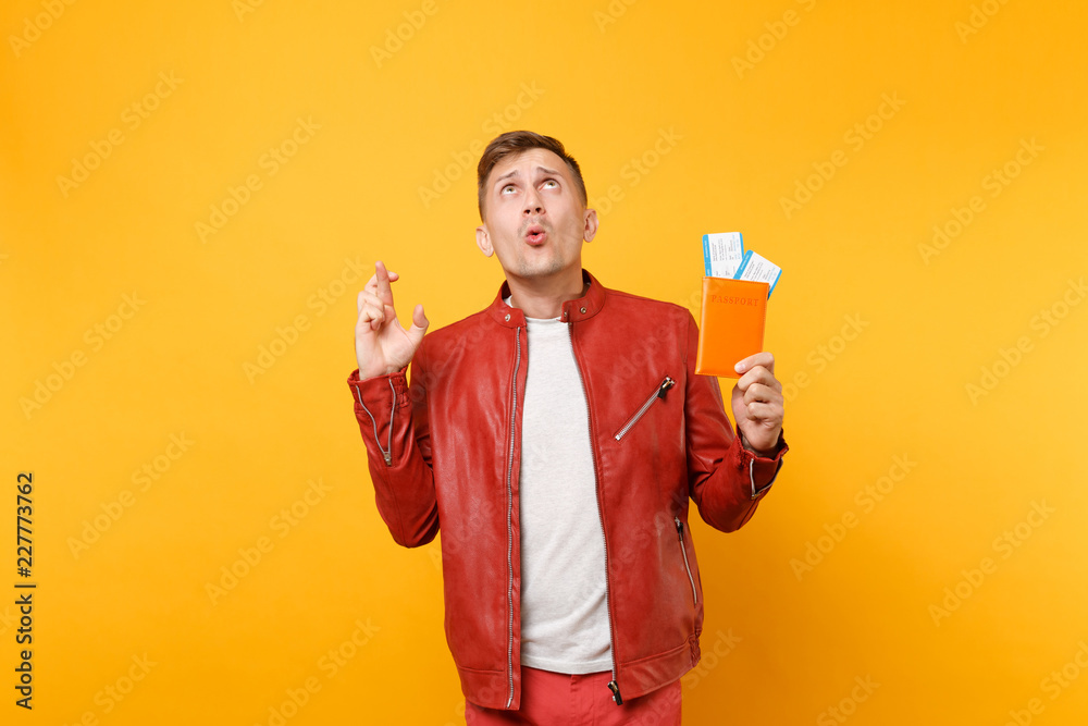 Portrait vogue smiling handsome young man in red leather jacket t-shirt hold passport tickets isolated on bright trending yellow background. People sincere emotions lifestyle concept. Advertising area Portrait vogue smiling handsome young man in red leather jacket t-shirt hold passport tickets isolated on bright trending yellow background. People sincere emotions lifestyle concept. Advertising area