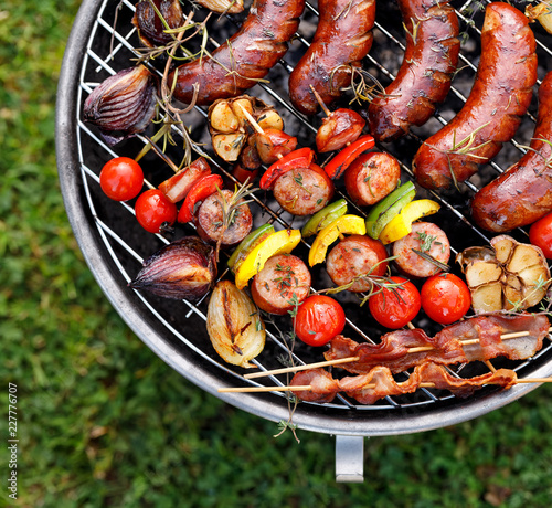Grilled food. Various grilled products: Grilled sausages, meat and vegetable skewers, bacon and vegetables on the grill plate, outside. Barbecue, bbq
