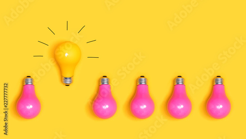 One outstanding idea concept with yellow and pink light bulbs photo