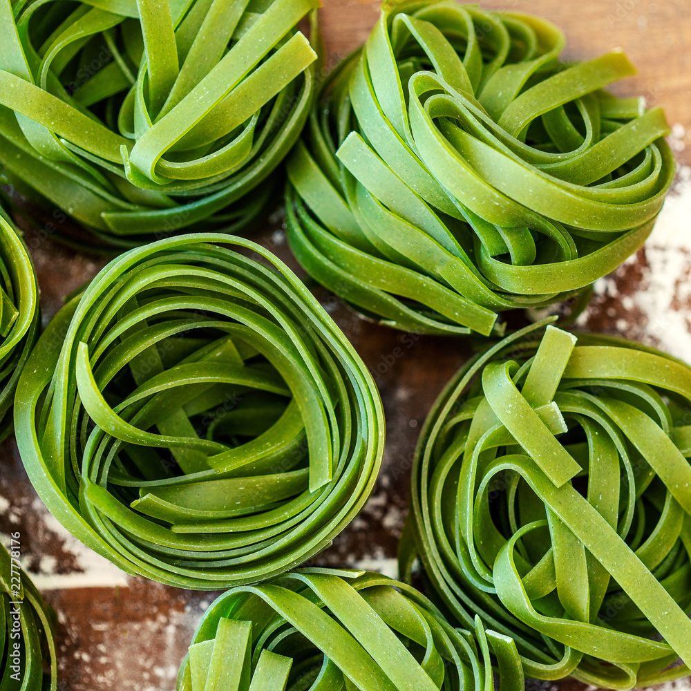 Egg Spinach Pasta Nest on wooden background, top view. Dry Pasta close up. Italian food concept . Egg Spinach Pasta Nest on wooden background, top view. Dry Pasta close up. Italian food concept .