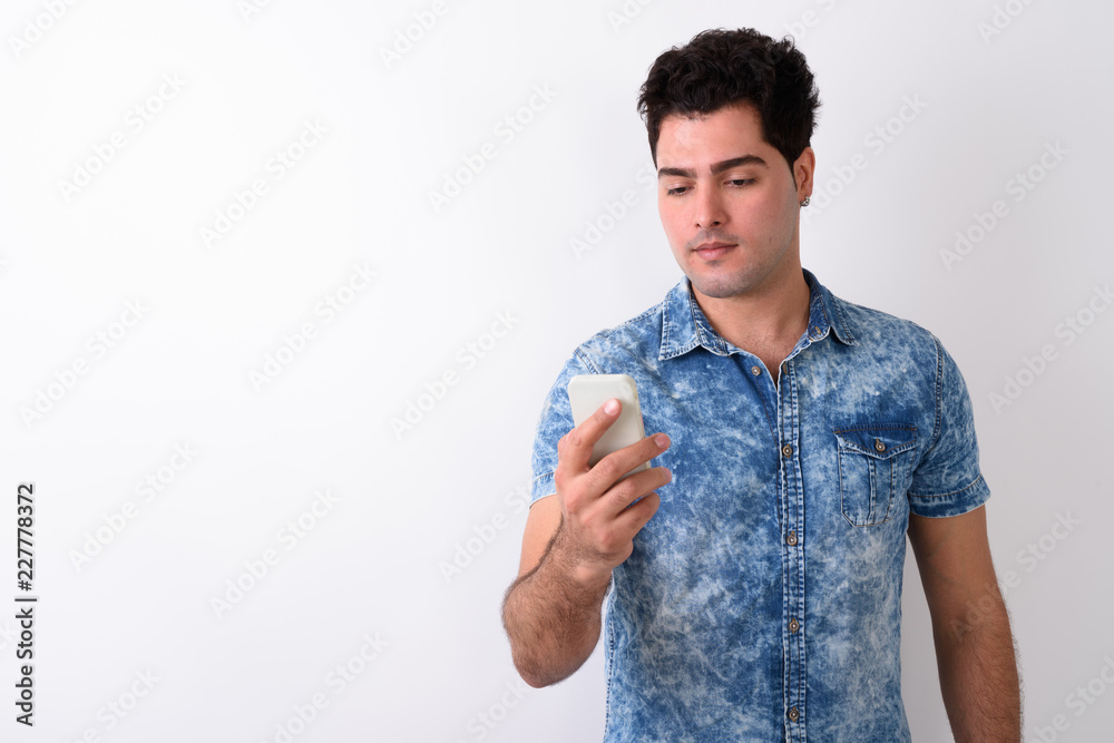 Young handsome Persian man using mobile phone against white back Young handsome Persian man using mobile phone against white back