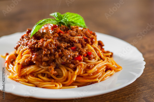 Traditional pasta spaghetti bolognese in white plate on wooden table background