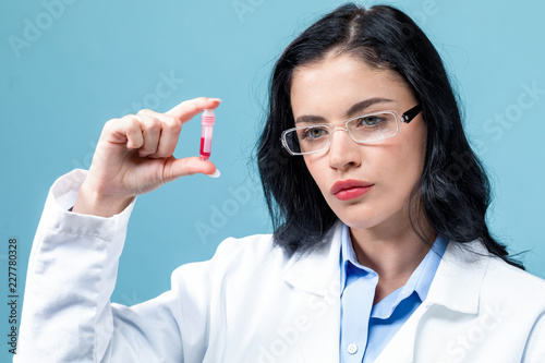 Laboratory scientist researcher with a test vial on a blue background