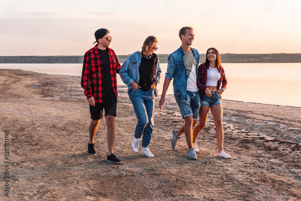 Group of hipster young friends on beach together walking during sunset. Freedom and friendship concept Group of hipster young friends on beach together walking during sunset. Freedom and friendship concept