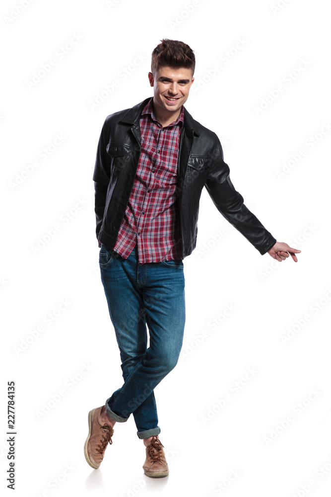 attractive young man snapping fingers while standing cross-legged attractive young man snapping fingers while standing cross-legged