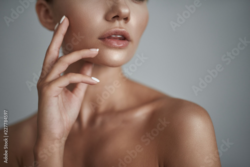 Laconic portrait of young attractive lady softly touching her right cheek while having her mouth opened