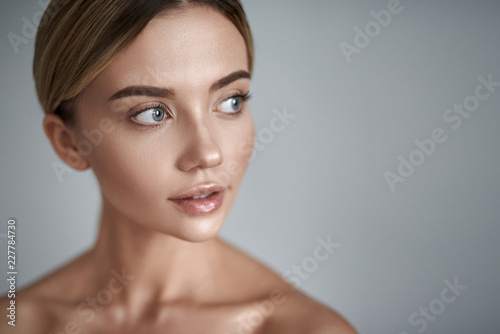 Interest. Young fair haired lady with clean skin having laconic make up and looking into the distance while standing alone