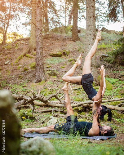 Giovane coppia pratica acroyoga in un bosco naturale photo