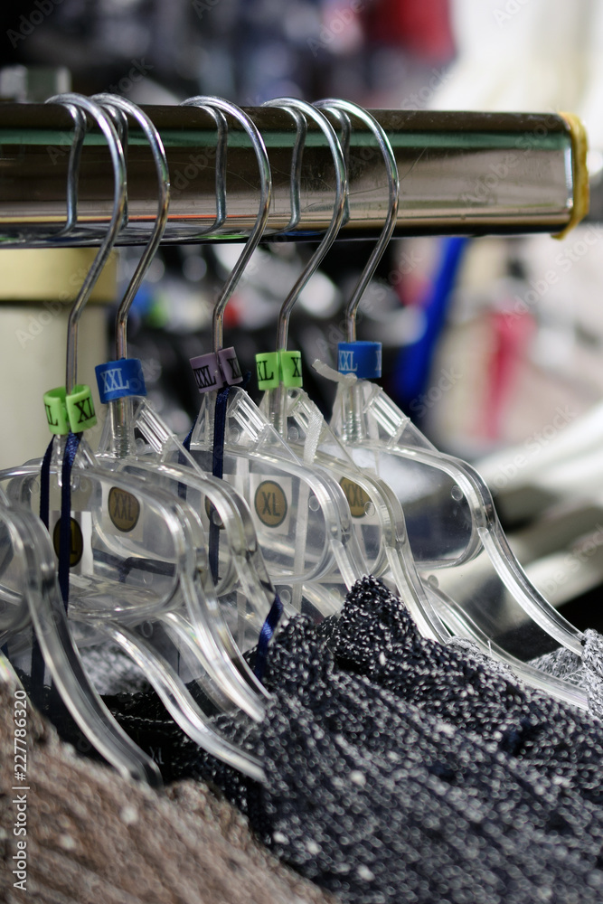 Women's new sweaters hanging on hangers. Only big sizes XL to XXXL. Vertical close up image.