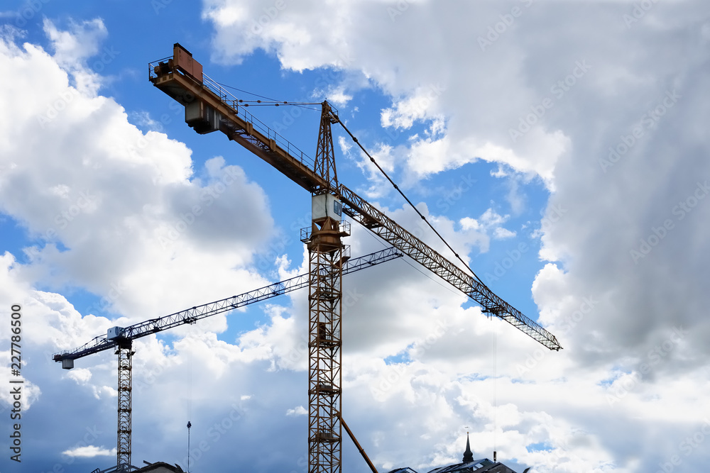 Towers cranes against a partly cloudy blue sky