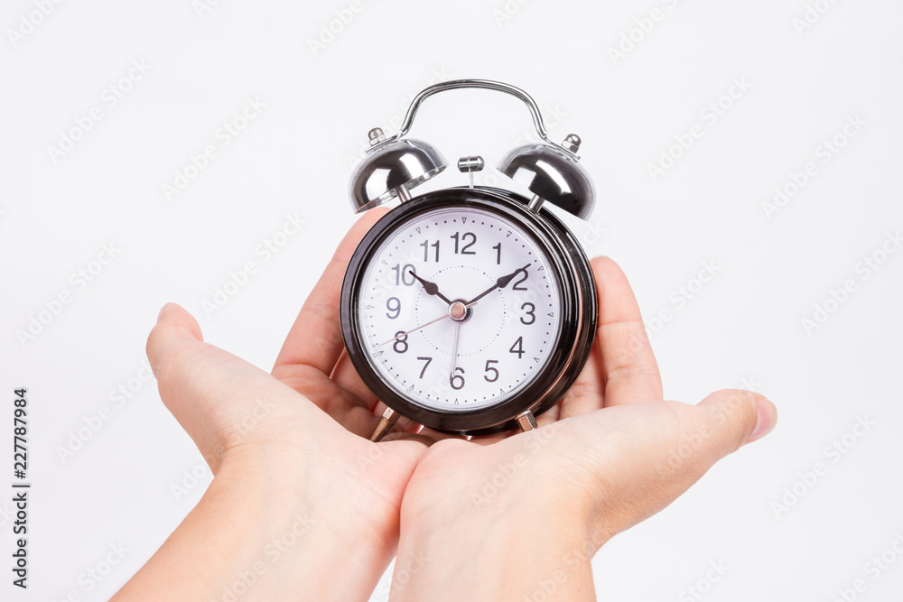 female hands hold black alarm clock isolated female hands hold black alarm clock isolated