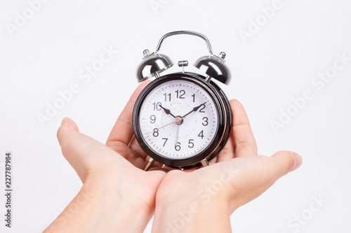 female hands hold black alarm clock isolated