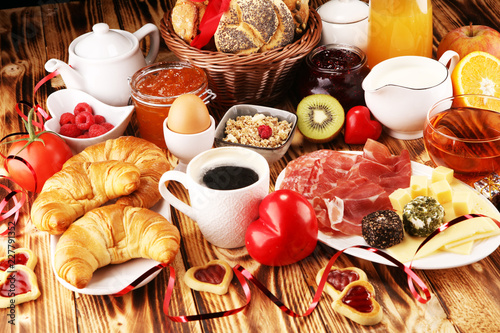 breakfast on table with bread buns, croissants, coffe and juice on valentines day.