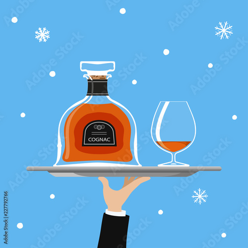 Bottle of cognac and glass on tray on blue background