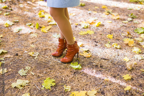 Autumn fashion. Female legs in stylish fashionable shoes boots, outdoor golden leaves