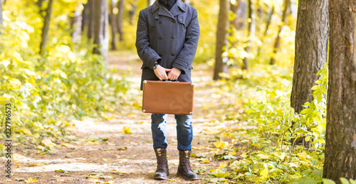 Fall, season and people concept - Close up of man standing with retro suitcase in park at autumn