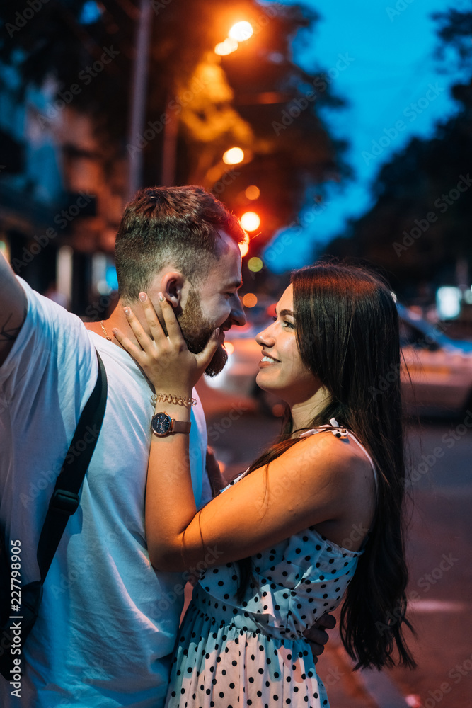 Young couple in the streets of the evening city - obrazy, fototapety, plakaty 