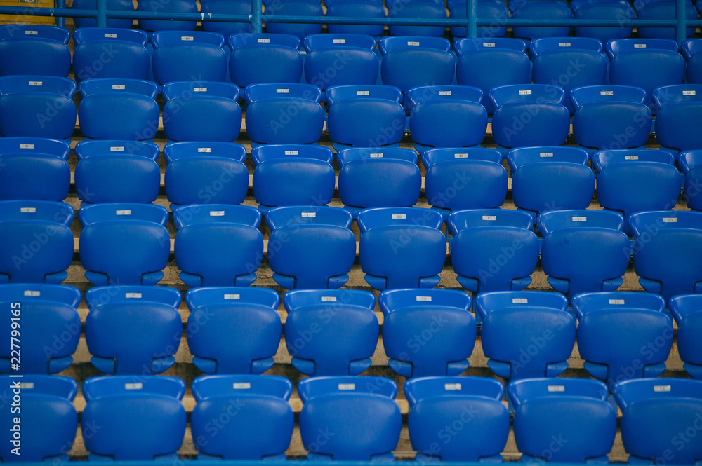 Naklejka premium Niebieskie puste miejsca na stadionie piłkarskim. Żółte schody z kilkoma sektorami.