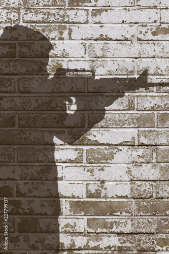 Mann zielt mit einem Gewehr. Schatten auf einer Wand.
