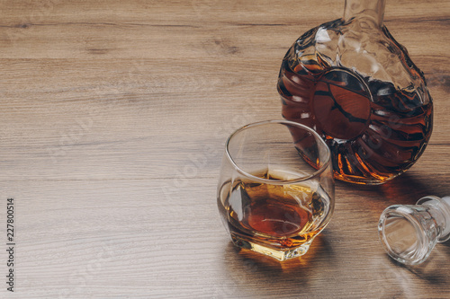 a glass of bourbon whiskey and a whiskey decanter on the wooden table